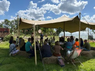 Een groep mensen buiten onder een partytent
